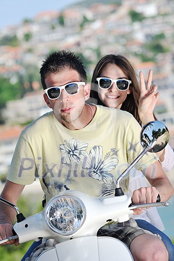 Portrait of happy young love couple on scooter enjoying themselves in a park at summer time