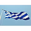 greece flag in wind at day with blue background