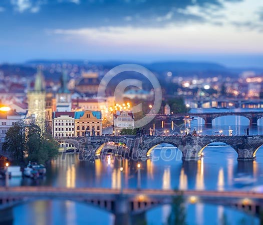 Travel Prague concept background - elevated view of bridges over Vltava river from Letna Park with tilt shift toy effect shallow depth of field. Prague, Czech Republic in twilight