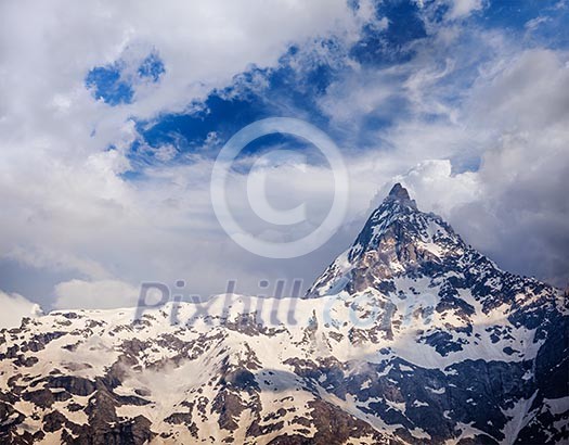 Snowcapped summit top of mountain in Himalayas in clouds. Himachal Pradesh, India