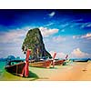 Vintage retro effect filtered hipster style travel image of long tail boat on tropical beach with limestone rock, Krabi, Thailand