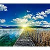 Pier in the lake in countryside on sunset with sunrays, Bavaria, Germany