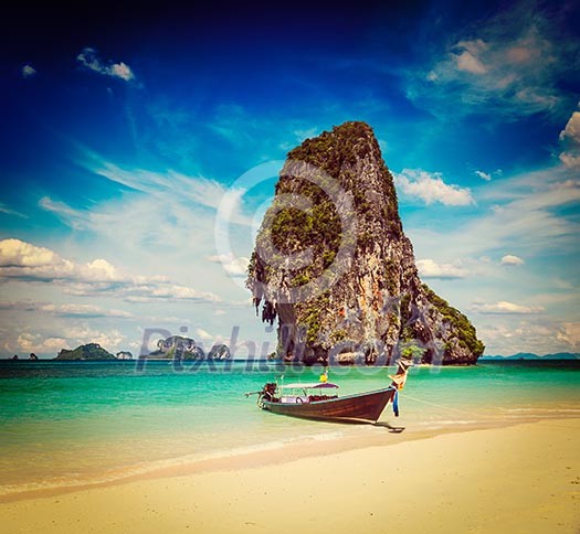 Vintage retro effect filtered hipster style travel image of long tail boat on tropical beach with limestone rock, Krabi, Thailand