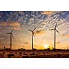 Green renewable energy concept - wind generator turbines sihouettes on sunset