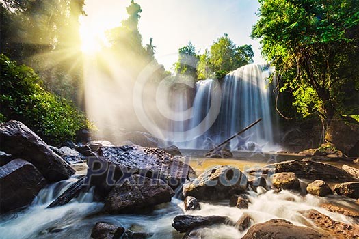 Tropical waterfall with sun rays in Cambodia Tropical waterfall with sun rays in Cambodia