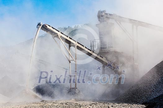Industrial background - crusher rock stone crushing machine at open pit mining and processing plant for crushed stone, sand and gravel Industrial background - crusher rock stone crushing machine at open pit mining and processing plant for crushed stone, sand and gravel