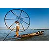 Myanmar travel attraction landmark - Traditional Burmese fisherman with fishing net at Inle lake in Myanmar famous for their distinctive one legged rowing style