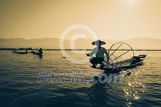 Myanmar travel attraction landmark - Traditional Burmese fisherman at Inle lake, Myanmar famous for their distinctive one legged rowing style Myanmar travel attraction landmark - Traditional Burmese fisherman at Inle lake, Myanmar famous for their distinctive one legged rowing style