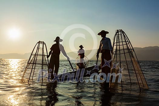Myanmar travel attraction landmark - three traditional Burmese fishermen at Inle lake, Myanmar famous for their distinctive one legged rowing style Myanmar travel attraction landmark - three traditional Burmese fishermen at Inle lake, Myanmar famous for their distinctive one legged rowing style