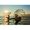 Myanmar travel attraction landmark - two traditional Burmese fishermen at Inle lake, Myanmar famous for their distinctive one legged rowing style on sunrise sunset