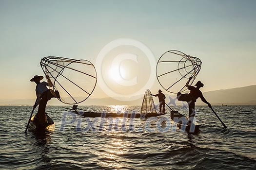 Myanmar travel attraction landmark - three traditional Burmese fishermen at Inle lake, Myanmar famous for their distinctive one legged rowing style Myanmar travel attraction landmark - three traditional Burmese fishermen at Inle lake, Myanmar famous for their distinctive one legged rowing style