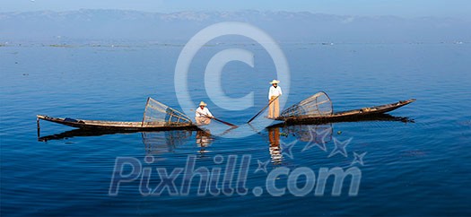 Panorama of traditional Burmese fishermen with fishing net at Inle lake in Myanmar famous for their distinctive one legged rowing style Panorama of traditional Burmese fishermen with fishing net at Inle lake in Myanmar famous for their distinctive one legged rowing style