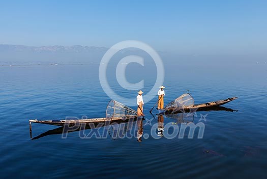 Myanmar travel attraction landmark - Traditional Burmese fishermen with fishing net at Inle lake in Myanmar famous for their distinctive one legged rowing style Myanmar travel attraction landmark - Traditional Burmese fishermen with fishing net at Inle lake in Myanmar famous for their distinctive one legged rowing style