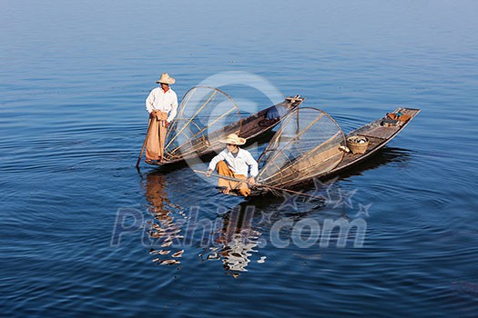 Myanmar travel attraction landmark - Traditional Burmese fishermen with fishing net at Inle lake in Myanmar famous for their distinctive one legged rowing style Myanmar travel attraction landmark - Traditional Burmese fishermen with fishing net at Inle lake in Myanmar famous for their distinctive one legged rowing style