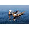 Myanmar travel attraction landmark - Traditional Burmese fishermen with fishing net at Inle lake in Myanmar famous for their distinctive one legged rowing style