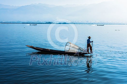 Myanmar travel attraction landmark - Traditional Burmese fisherman at Inle lake, Myanmar famous for their distinctive one legged rowing style Myanmar travel attraction landmark - Traditional Burmese fisherman at Inle lake, Myanmar famous for their distinctive one legged rowing style