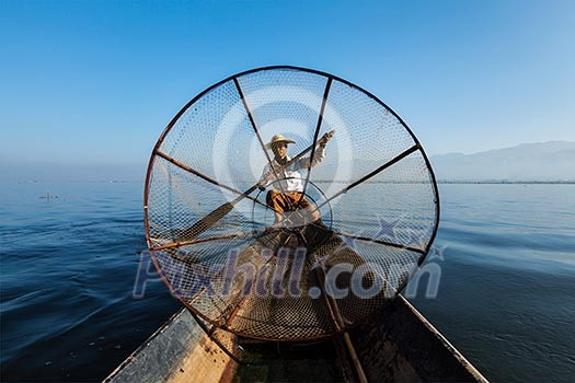 Myanmar travel attraction landmark - Traditional Burmese fisherman with fishing net at Inle lake in Myanmar famous for their distinctive one legged rowing style, view from boat Myanmar travel attraction landmark - Traditional Burmese fisherman with fishing net at Inle lake in Myanmar famous for their distinctive one legged rowing style, view from boat