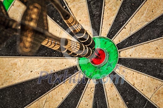 Success hitting target aim goal achievement concept background - three darts in bull's eye close up Success hitting target aim goal achievement concept background - three darts in bull's eye close up