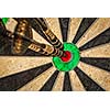 Success hitting target aim goal achievement concept background - three darts in bull's eye close up