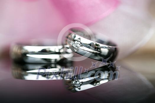 Two splendid wedding rings on a wedding day, shot on a reflective surface. Love concept.