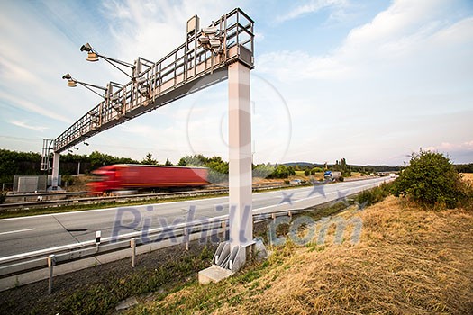truck passing through a toll gate on a highway (motion blurred image; color toned image) truck passing through a toll gate on a highway (motion blurred image; color toned image)