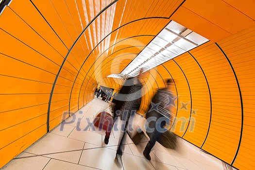 People rushing through a subway corridor (motion blur technique is used to convey movement)