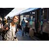 Pretty young woman boarding a train/having arrived to her destination, waiting for her friends to pick her up (color toned image)