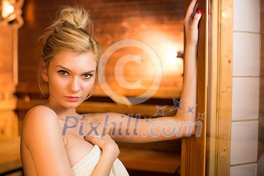 Young woman relaxing in a sauna, taking a break from her busy schedule, taking care of herself, enjoying the wellness benefits her job provides Young woman relaxing in a sauna, taking a break from her busy schedule, taking care of herself, enjoying the wellness benefits her job provides