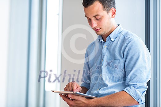 Handsome young man using his tablet computer (color toned image; shallow DOF)