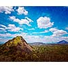 Vintage retro hipster style travel image of sky above small mountains, covered with trees with grunge texture overlaid. Sri Lanka