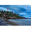 Gathering storm on beach and Kovalam (Vizhinjam) lighthouse on stormy sunset. Kerala, India
