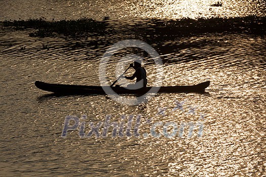 Man in canoe on sunrise. Kerala backwaters, India Man in canoe on sunrise. Kerala backwaters, India