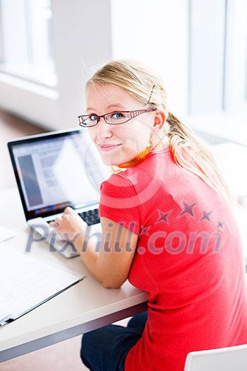 In the library - pretty, female student with books, papers and laptop computer working in a high school library (color toned image)