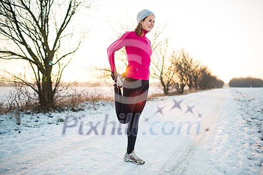Young woman stretching while running outdoors on a cold winter evening