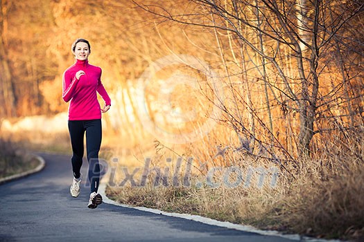 Young woman running outdoors in a city park on a cold fall/winter day