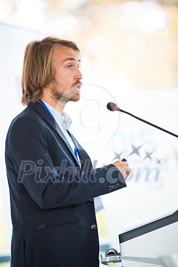 Handsome young man giving a speech at a conference Handsome young man giving a speech at a conference