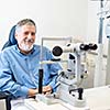 Optometry concept - Senior patient sitting the exmanination chair , before having his eyes examined by an eye doctor, smiling, looking happy