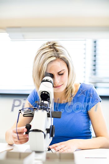 Pretty, female optometrist measuring newly made glasses - veryfing it is spot on