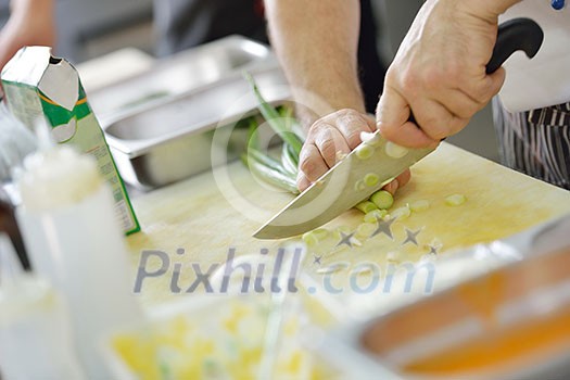 Handsome chef dressed in white uniform decorating pasta salad and seafood fish in modern kitchen