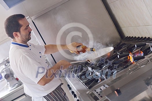 Handsome chef dressed in white uniform decorating pasta salad and seafood fish in modern kitchen Handsome chef dressed in white uniform decorating pasta salad and seafood fish in modern kitchen