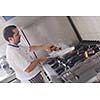 Handsome chef dressed in white uniform decorating pasta salad and seafood fish in modern kitchen