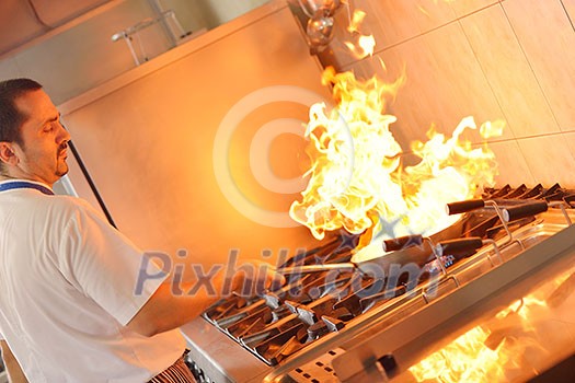 Handsome chef dressed in white uniform decorating pasta salad and seafood fish in modern kitchen