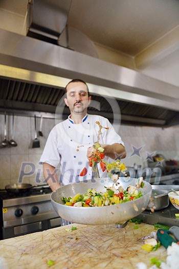 Handsome chef dressed in white uniform decorating pasta salad and seafood fish in modern kitchen Handsome chef dressed in white uniform decorating pasta salad and seafood fish in modern kitchen