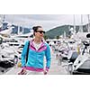 relaxed young woman walking in marina with yacht boats in bacground