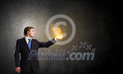 Young businessman holding fire flames in palm Young businessman holding fire flames in palm