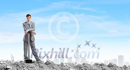 Young businessman with hammer standing on ruins