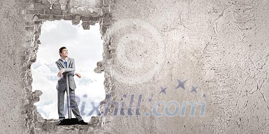 Young businessman with big hammer against wall