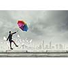 Young businesswoman walking on roof with colorful umbrella