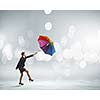 Young businesswoman walking with colorful umbrella against bokeh background
