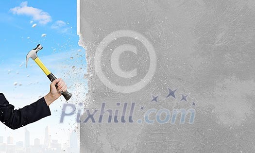 Close up of female hand crashing wall with hammer Close up of female hand crashing wall with hammer